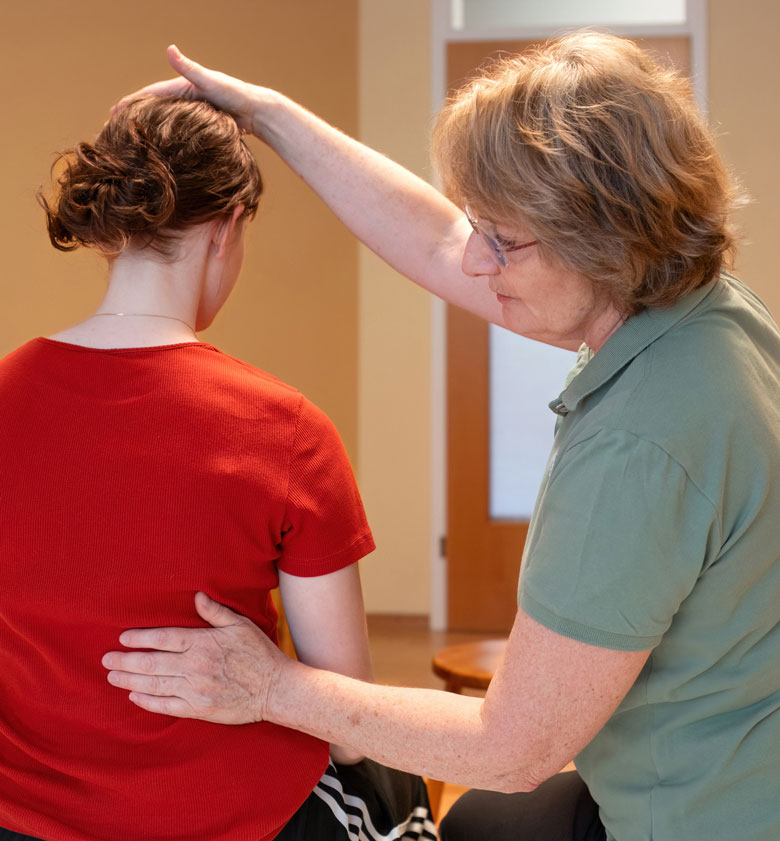 Eine Person bei Feldenkrais Übung unterstützt von Practitioner Ingrid Seeber-Grosek